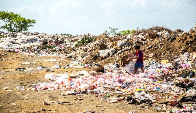 Photo of child rummaging through landfill full of plastic