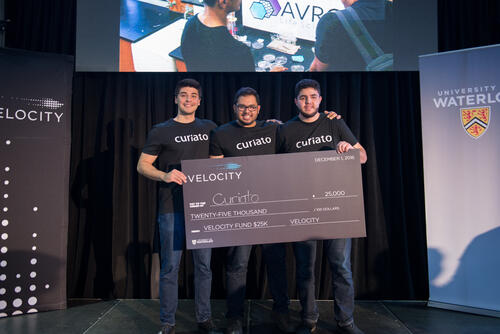 Curiato founders (Khan centre) hold up $25,000 check after winning Velocity pitch competition.