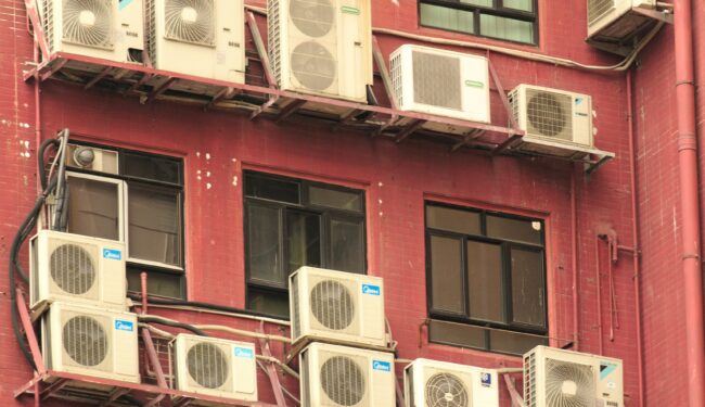 Image of group of air conditioners on side of a pink-coloured building