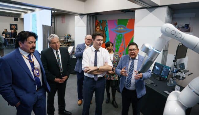 Prime Minister Trudeau, Minister Ien and Minister Vandal look at Cobionix's robot Codi at the Saskatchewan Indian Institute of Technologies in Saskatoon.