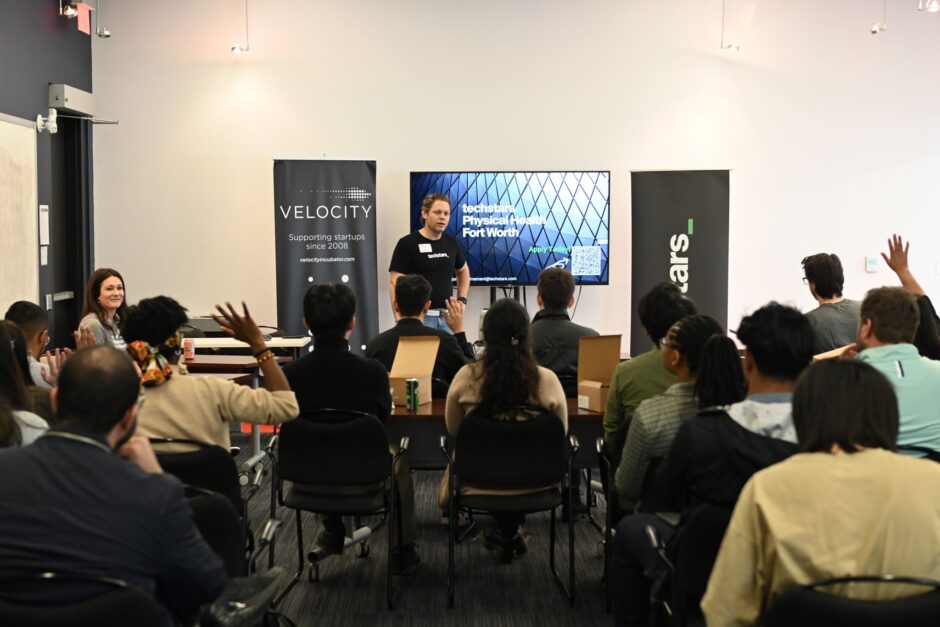 Techstars representative standing in front of a TV screen speak to a group of engaged founders at Velocity