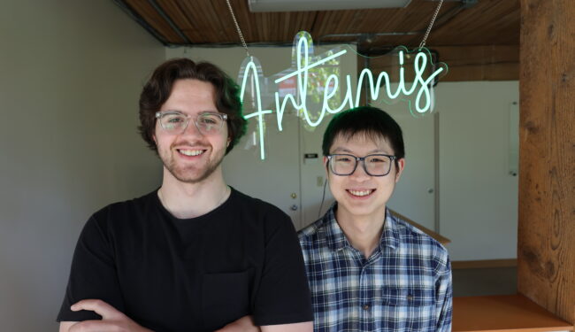 Artemis Data co-founders stand in front of neon green sign that says Artemis