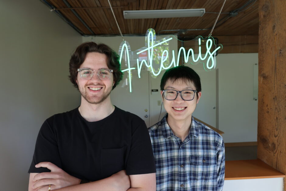 Artemis Data co-founders stand in front of neon green sign that says Artemis