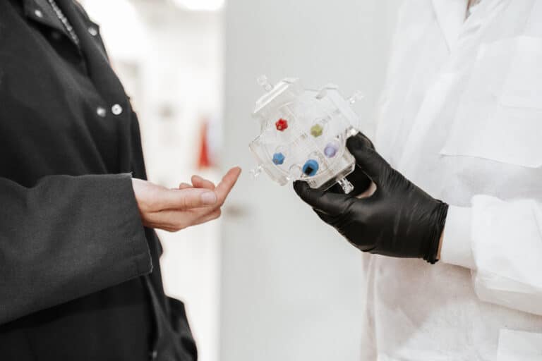 One person holding Membio's bioreactor tech with another person pointing to it.