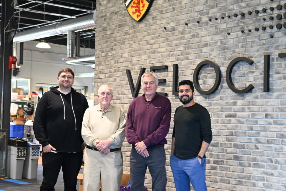 A photo of four men standing in front of the Velocity logo