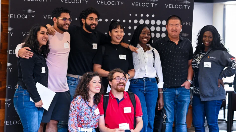 A group of people stand in front of Velocity banner.